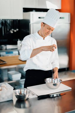 Restaurant professional kitchen: chef prepares delicious dish, beats eggs in a bowl