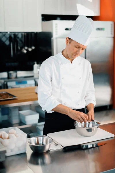 Restaurant professional kitchen: chef prepares delicious dish, beats eggs in a bowl
