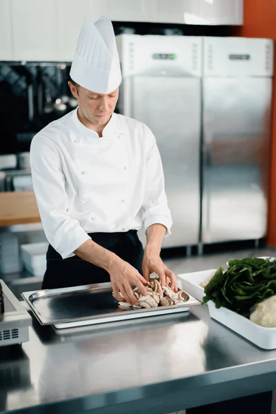 Professional kitchen: chef prepare food. The cook cuts mushrooms to prepare delicious dish.