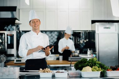 Professional kitchen of a restaurant, male chef checks the availability of products from an employee. Restaurant warehouse analytics. Preaplist checking