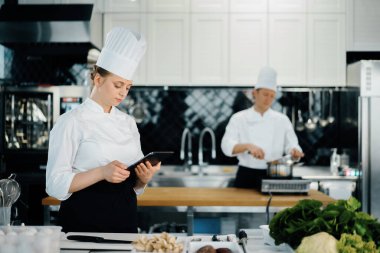 Professional kitchen of a restaurant, female chef checks the availability of products from an employee. Restaurant warehouse analytics. Preaplist checking