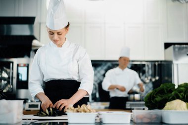Professional restaurant kitchen, woman chef cuts a zucchini