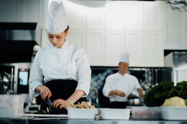 Professional restaurant kitchen, woman chef cuts a zucchini