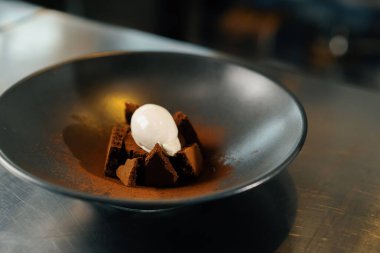Close-up of a chef putting ice cream on a brownie in a professional kitchen restaurant