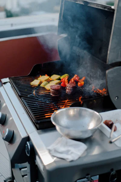 Close-up: vegetables and meat filet mignon on a barbecue grill on the rooftop of a skyscraper. Fire in the barbecue