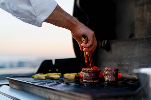 Vegetables and meat filet mignon on a barbecue grill on the rooftop of a skyscraper. Fire in barbecue.