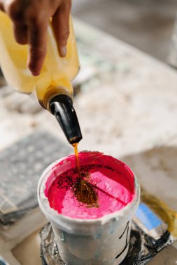 Artisan artist mixing paint in his workshop. Pink paint, paint mixer