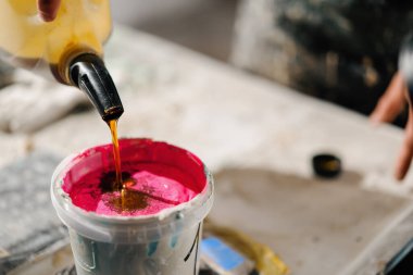 Artisan artist mixing paint in his workshop. Pink paint, paint mixer