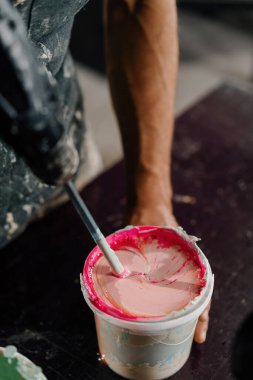 Artisan artist mixing paint in his workshop. Pink paint, paint mixer