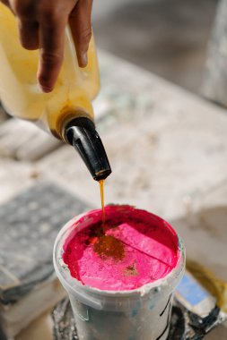 Artisan artist mixing paint in his workshop. Pink paint, paint mixer