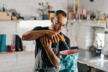 Close-up: artisan sculptor artist creates handmade vase in his workshop