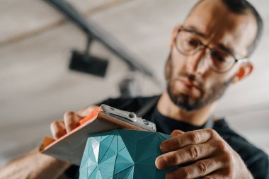 Close-up: artisan sculptor artist man works with sandpaper.