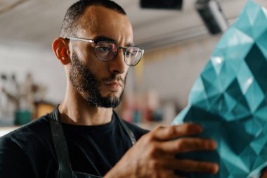 Male artist sculptor artisan works seriously in workshop.