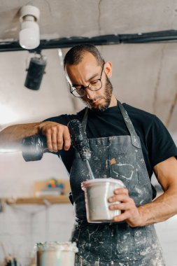 Artisan artist mixing paint in his workshop. Pink paint, paint mixer