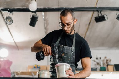 Artisan artist mixing paint in his workshop. Pink paint, paint mixer