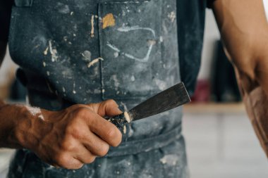 Male painter sculptor artisan works with spatula in workshop