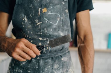 Male painter sculptor artisan works with spatula in workshop