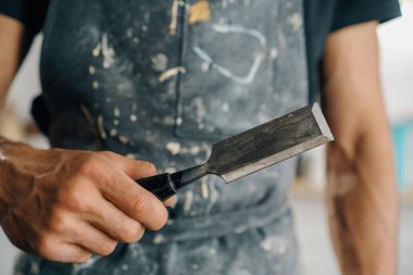 Male painter sculptor artisan works with spatula in workshop