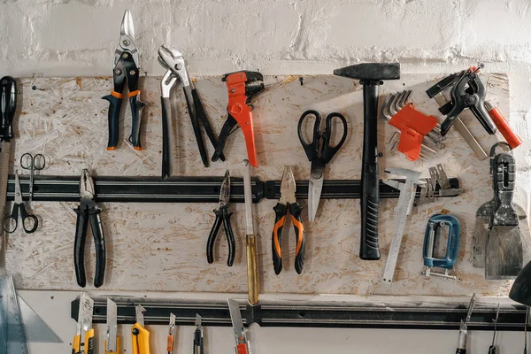 Wall with tools in art workshop: scissors, hammer, pliers, blades