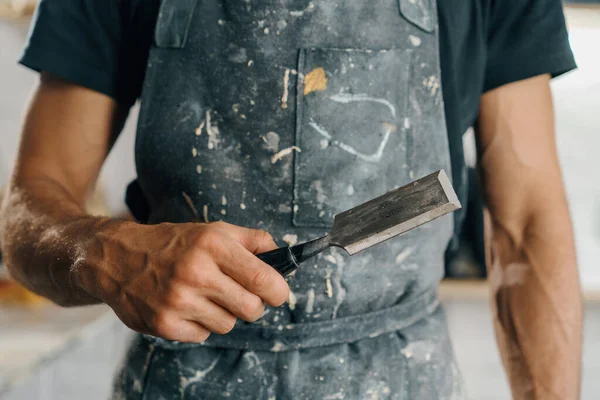 Male painter sculptor artisan works with spatula in workshop