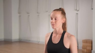 Relaxed young woman is meditating in lotus position sitting on yoga mat with closed eyes and hands in namaste