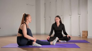 Two sports girls after yoga Pilates communicate while sitting in lotus position. Rest and relax