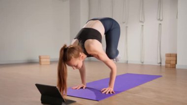 Fitness coach teaching yoga online to group of people. People practicing yoga with trainer with video conference.