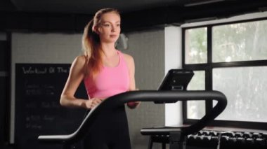 Woman athlete running on treadmill, doing cardio workout in the gym