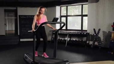 Woman athlete running on treadmill, doing cardio workout in the gym