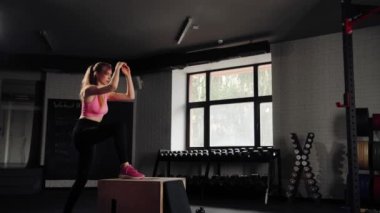 Woman athlete doing cardio exercise with lifting on pylo box in gym.