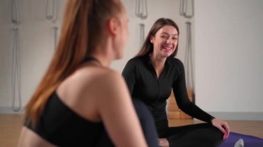 Two athletic women are resting after yoga training and chatting. Workout for health.