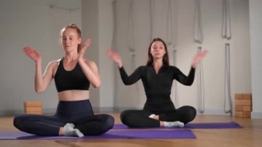 Two athletic women are doing yoga for health. girls in lotus position