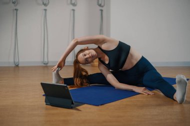 Athletic woman doing yoga pilates stretching online workout in studio or at home