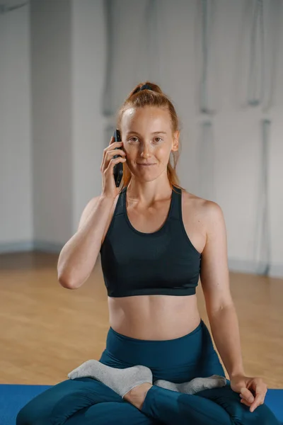 Athletic woman talking on the phone while doing pilates yoga stretching for health in studio. athletic body girl