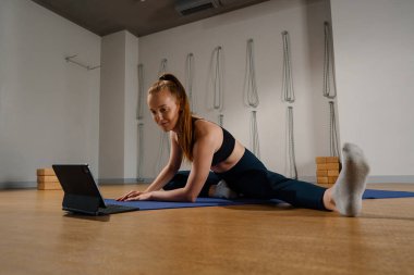 Athletic woman doing yoga pilates stretching online workout in studio or at home