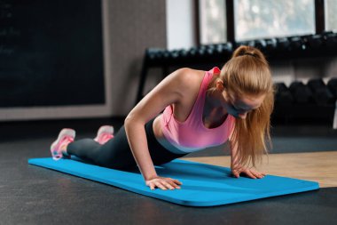 Athletic woman is engaged in training push-ups in gym. chest and arm exercises