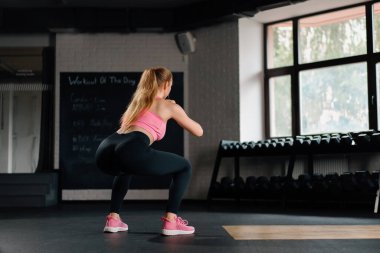 Athletic woman doing squats with a weight in gym. Mobility and Leg Exercise Workout