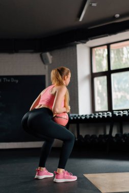 Athletic woman doing squats with a weight in gym. Mobility and Leg Exercise Workout