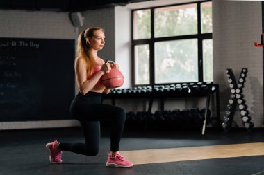 Athletic woman doing squats with a weight in gym. Mobility and Leg Exercise Workout
