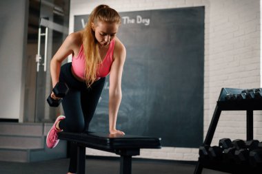 Athletic woman doing dumbbell traction in the gym. back workout.