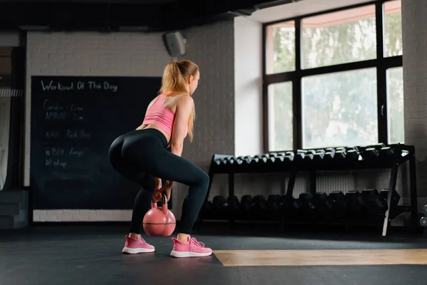 Athletic woman doing squats with a weight in gym. Mobility and Leg Exercise Workout