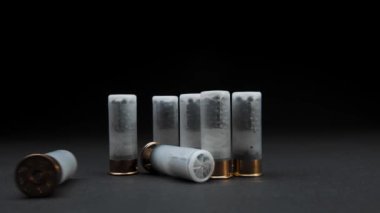 Close-up: Shotgun shells are on the table against a dark background, one cartridge is rolled into frame