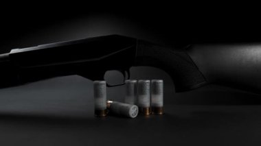 Close-up: light glides over a hunting shotgun with cartridges on a table against dark background