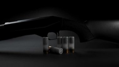 Close-up: light glides over a hunting shotgun with cartridges on a table against dark background