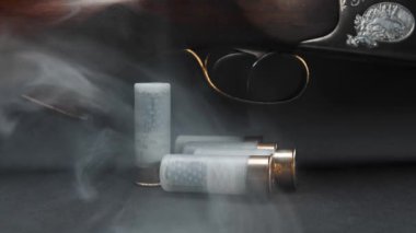 Close-up: a wooden hunting shotgun with cartridges on a table against dark background