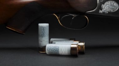 Close-up: a wooden hunting shotgun with cartridges on a table against dark background