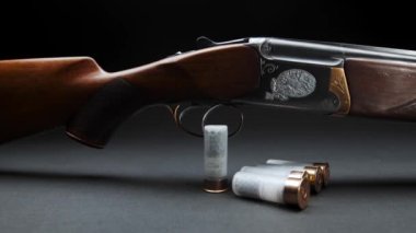 Close-up: a wooden hunting shotgun with cartridges on a table against dark background