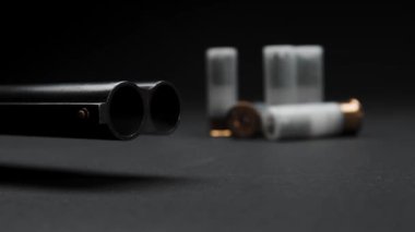 Close-up of a loaded shotgun after being fired and cartridges on table in smoke