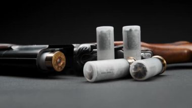 Close-up of a loaded shotgun after being fired and cartridges on table in smoke
