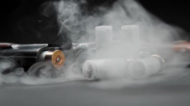 Close-up of a loaded shotgun and ammo on table in smoke